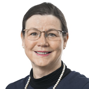 Eine Person mit Brille, dunklem Oberteil und Perlenkette lächelt selbstbewusst vor einem weißen Hintergrund. Ihr Haar ist ordentlich zurückgekämmt und strahlt die geschliffene Professionalität aus, die für jemanden im Büromanagement typisch ist.