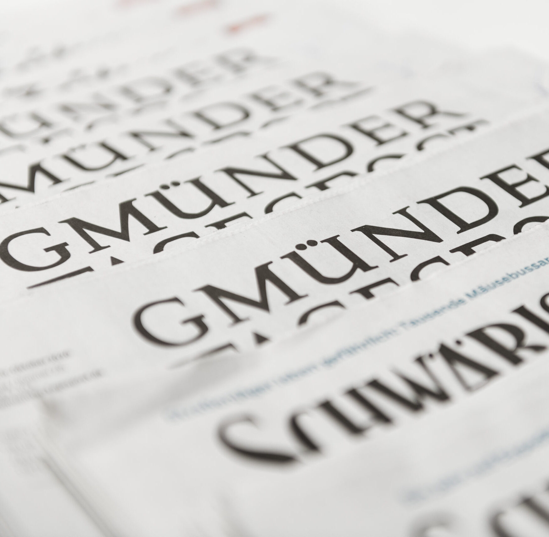 Auf einer hellen Unterlage liegt ein Stapel Zeitungen mit Schlagzeilen der „Gmünder Tagespost“ und der „Schwäbischen“. Unter anderem geht es um das Thema Pflege und die Bedeutung des Corona-Bonus.