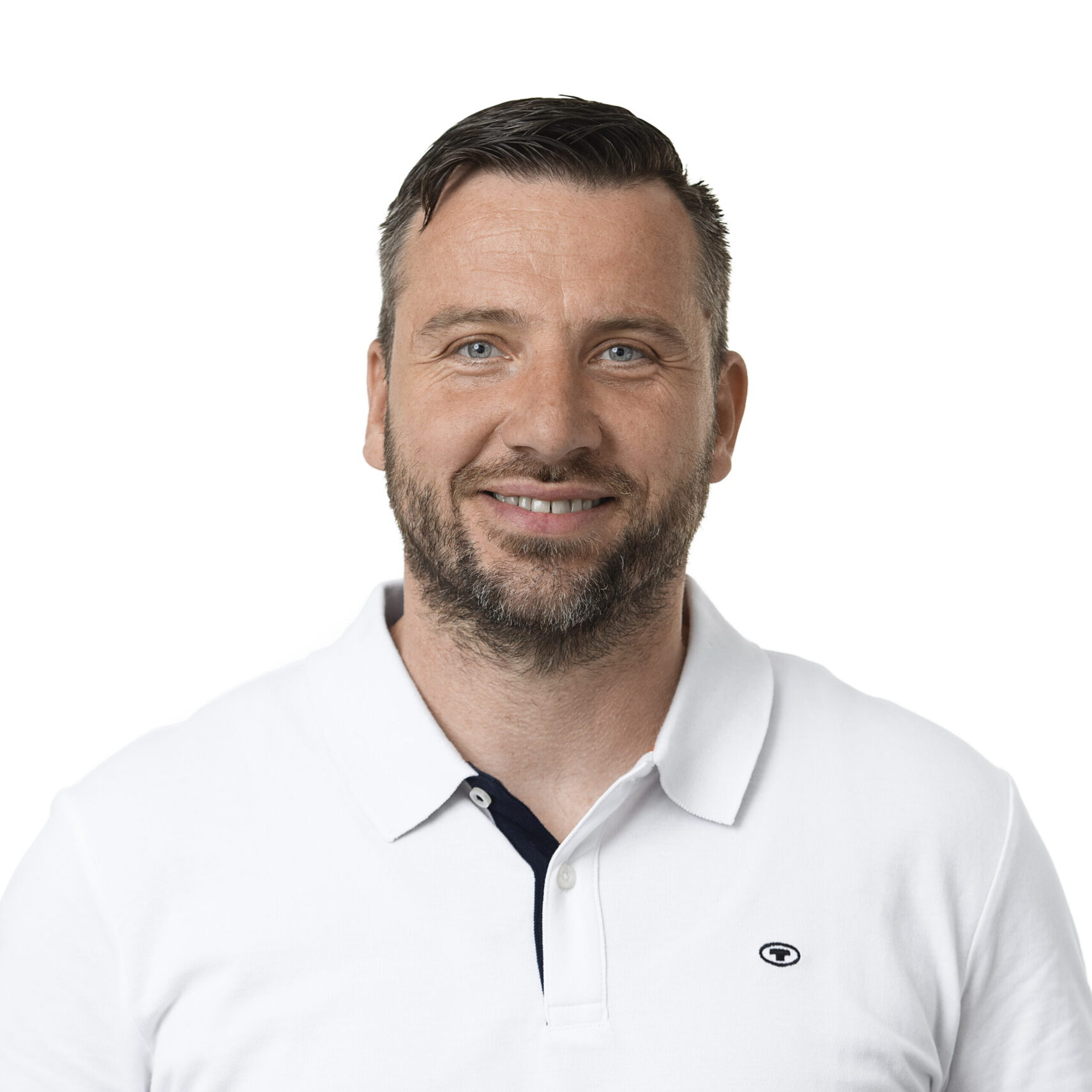 Ein lächelnder Mann mit kurzen, dunklen Haaren und Bart, der ein weißes Poloshirt vor einem schlichten weißen Hintergrund trägt, verkörpert den Geist von Vinzenz von Paul Werkstatt.