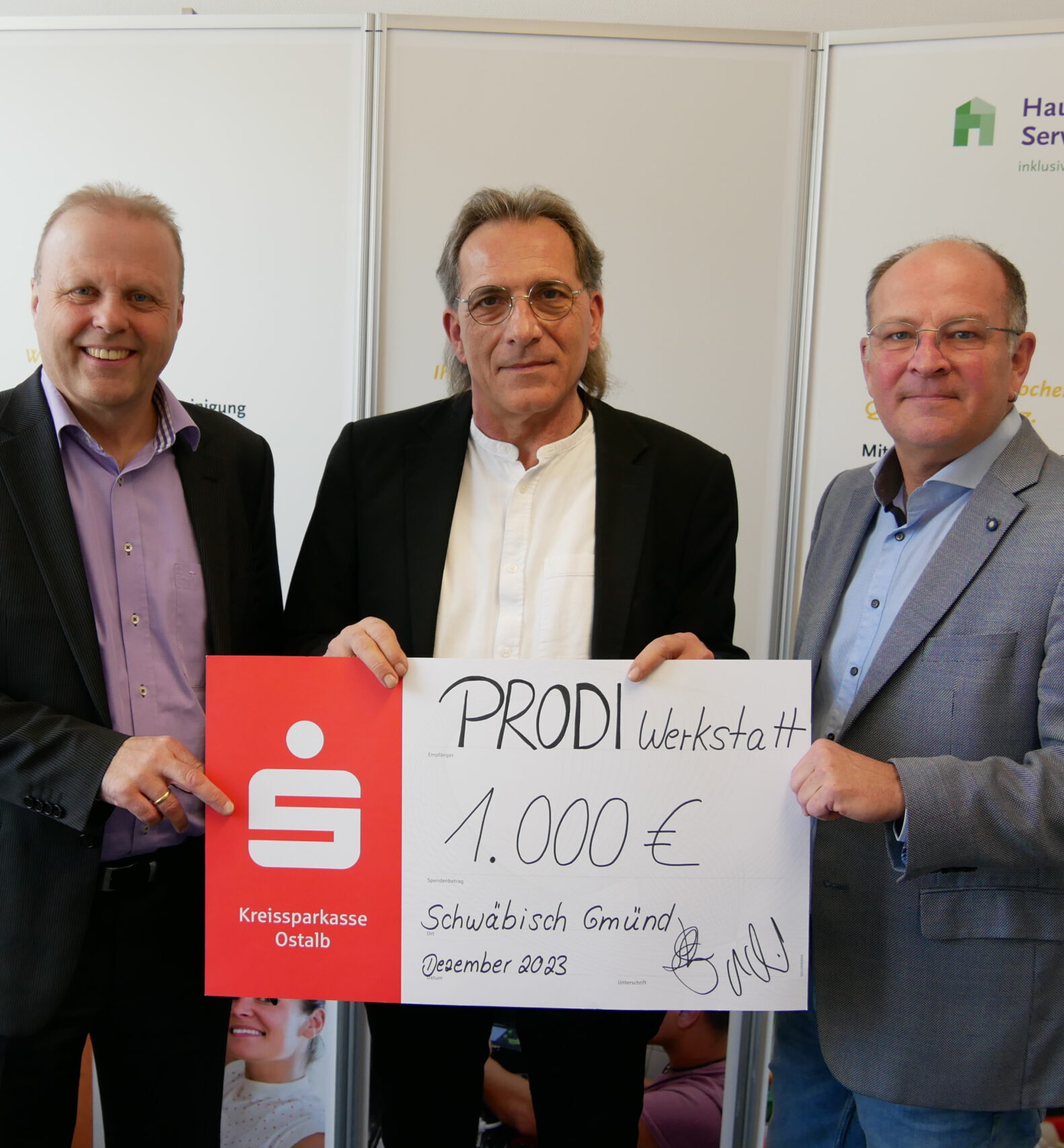 Drei Männer stehen stolz zusammen in Bargau und halten einen großen Scheck über 1.000 Euro in den Händen, ausgestellt auf die „PRODI-Werkstatt“ als großzügige Spende der Kreissparkasse Ostalb, datiert auf Dezember 2023. Sie tragen Anzüge, zwei von ihnen tragen Brillen.