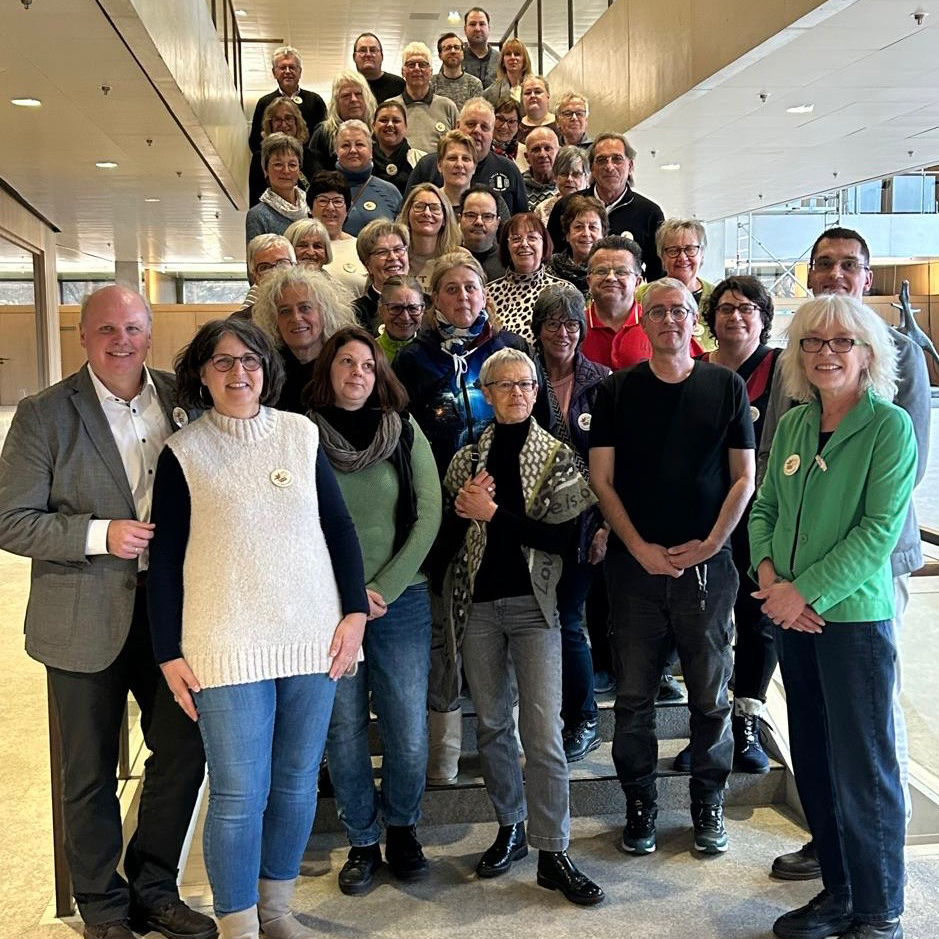 Eine Gruppe von etwa vierzig Erwachsenen, die lächelnd zusammen auf einer Innentreppe in einem Foyer eines Gebäudes posieren, feiert 10 Jahre Kunstprojekte. Sie sind leger gekleidet und scheinen an einer Gruppenveranstaltung oder einem Treffen teilzunehmen. Eine Gruppe von etwa vierzig Erwachsenen, die lächelnd zusammen auf einer Innentreppe in einem Foyer eines Gebäudes posieren, feiert 10 Jahre Kunstprojekte. Sie sind leger gekleidet und scheinen an einer Gruppenveranstaltung oder einem Treffen teilzunehmen.