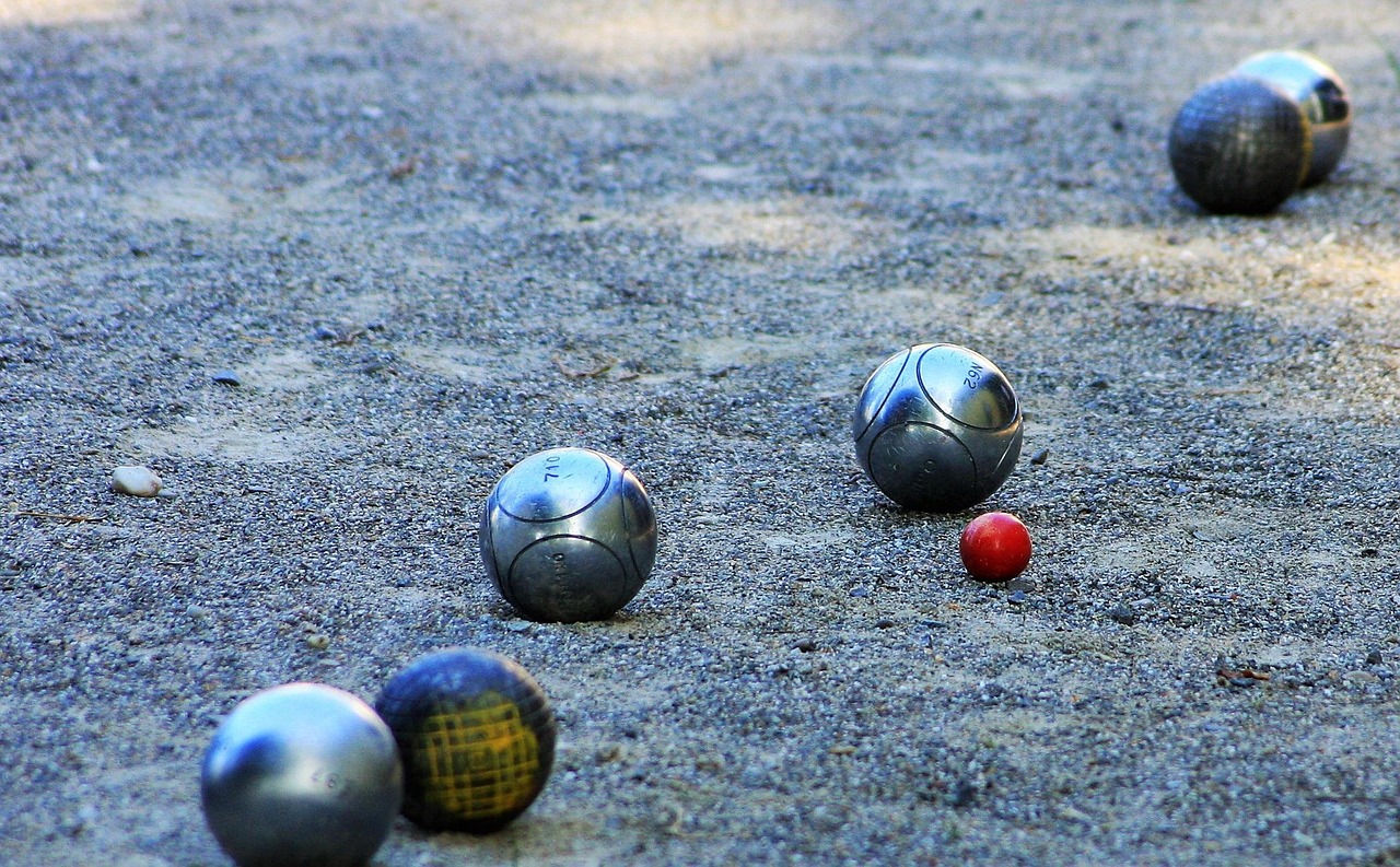 Mehrere metallene Pétanque-Kugeln und eine kleine rote Zielkugel (Cochonnet) liegen auf einer sandigen Spielfläche verstreut, was auf ein laufendes Spiel im Quartiersprojekt Wäschenbeuren schließen lässt. Mehrere metallene Pétanque-Kugeln und eine kleine rote Zielkugel (Cochonnet) liegen auf einer sandigen Spielfläche verstreut, was auf ein laufendes Spiel im Quartiersprojekt Wäschenbeuren schließen lässt.